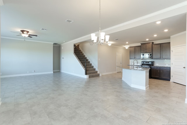 kitchen featuring dark brown cabinetry, light stone counters, ceiling fan with notable chandelier, backsplash, and a kitchen island with sink