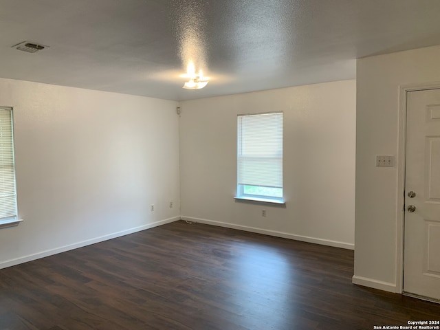 empty room with a textured ceiling and dark hardwood / wood-style flooring