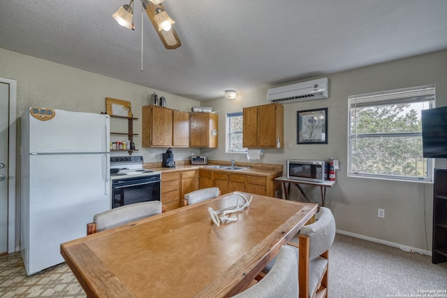 kitchen with a wall mounted AC, a textured ceiling, white appliances, and ceiling fan