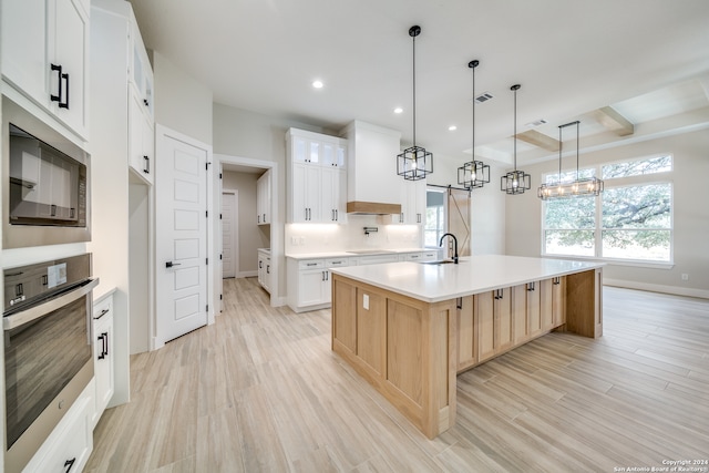 kitchen featuring a large island, white cabinets, light hardwood / wood-style flooring, and stainless steel appliances