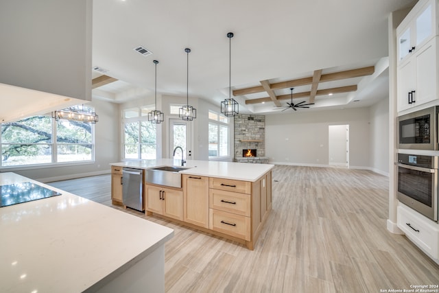 kitchen with appliances with stainless steel finishes, a kitchen island with sink, a fireplace, sink, and coffered ceiling