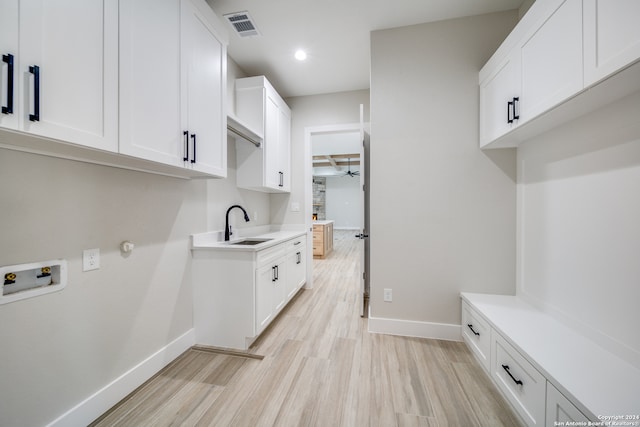 laundry area with sink, hookup for a washing machine, light wood-type flooring, and cabinets