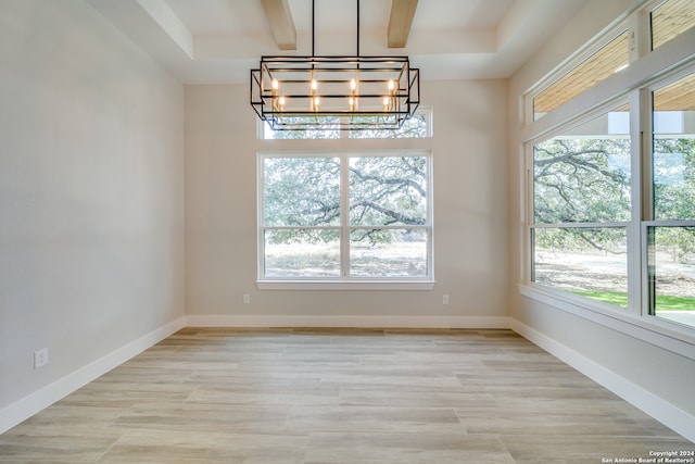 unfurnished dining area featuring a notable chandelier, beamed ceiling, and a wealth of natural light