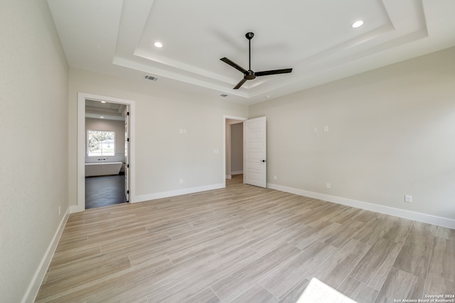 unfurnished bedroom with light hardwood / wood-style floors, a raised ceiling, and ceiling fan