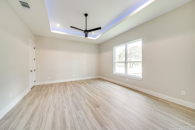 spare room featuring ceiling fan, a raised ceiling, and light hardwood / wood-style flooring