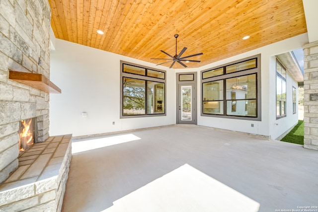 living room featuring a wealth of natural light, wood ceiling, concrete flooring, and an outdoor stone fireplace