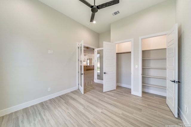 unfurnished bedroom with light hardwood / wood-style flooring, a high ceiling, and ceiling fan