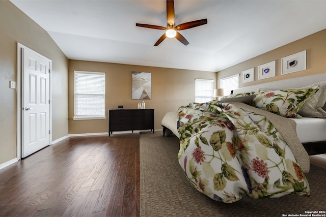 bedroom featuring multiple windows, dark wood-type flooring, vaulted ceiling, and ceiling fan