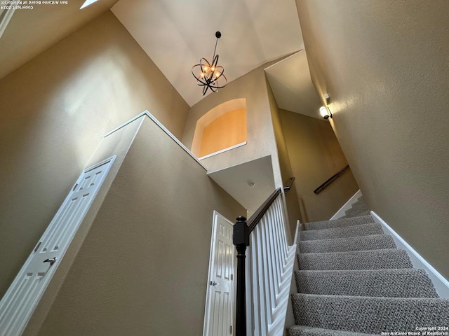 stairs featuring high vaulted ceiling and an inviting chandelier