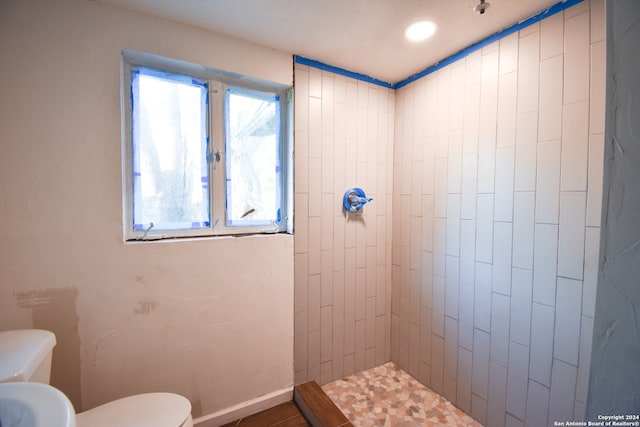 bathroom with toilet and a tile shower