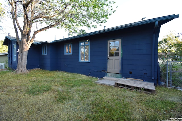 rear view of house with central air condition unit and a yard