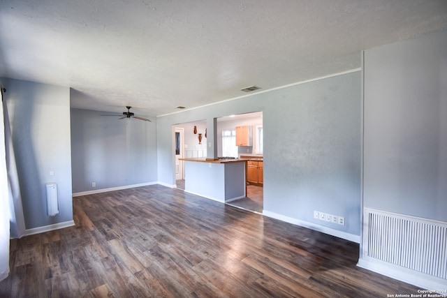 unfurnished living room with dark wood-type flooring, a textured ceiling, and ceiling fan