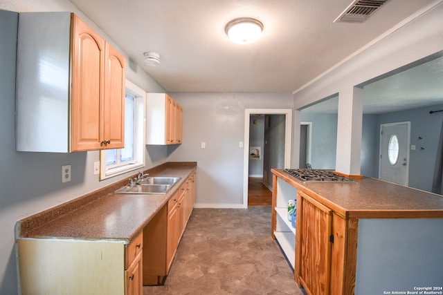 kitchen with stainless steel gas cooktop, sink, and light brown cabinetry