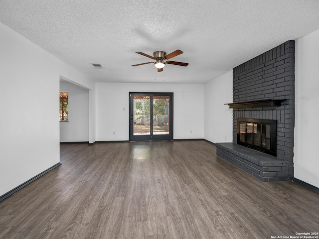 unfurnished living room with ceiling fan, a textured ceiling, dark hardwood / wood-style flooring, and a fireplace