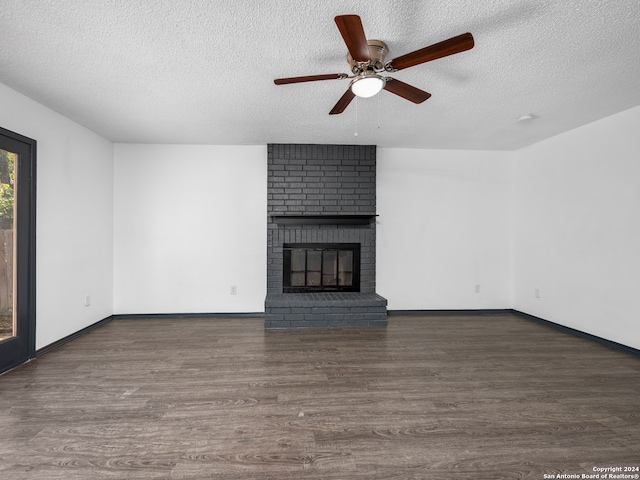 unfurnished living room with ceiling fan, a textured ceiling, a brick fireplace, and dark hardwood / wood-style floors