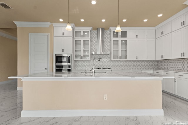 kitchen featuring decorative backsplash, wall chimney range hood, an island with sink, stainless steel appliances, and pendant lighting