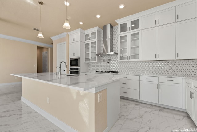 kitchen with hanging light fixtures, appliances with stainless steel finishes, wall chimney range hood, and white cabinets