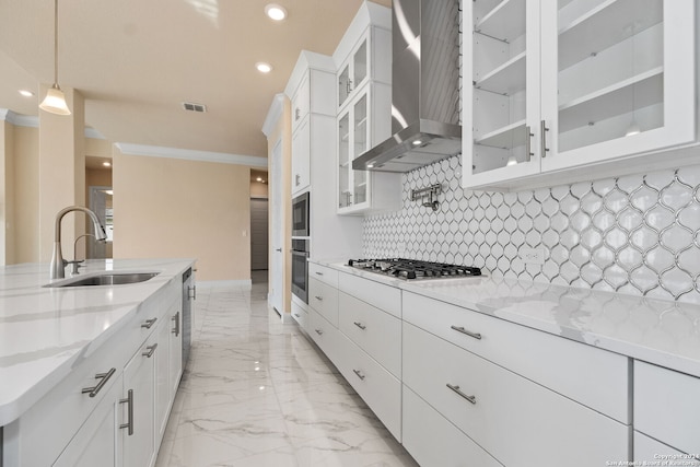 kitchen featuring wall chimney range hood, white cabinetry, sink, and appliances with stainless steel finishes