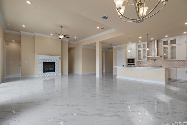 unfurnished living room featuring ceiling fan with notable chandelier, ornamental molding, sink, and a fireplace