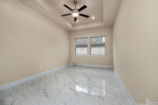 unfurnished room with ceiling fan and a raised ceiling