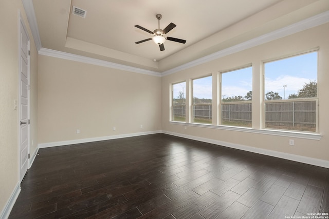 empty room featuring ornamental molding, ceiling fan, a raised ceiling, and dark hardwood / wood-style flooring