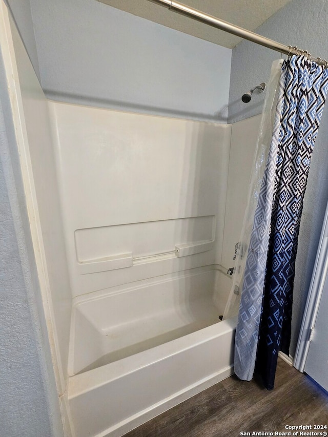 bathroom featuring wood-type flooring and shower / bath combo with shower curtain