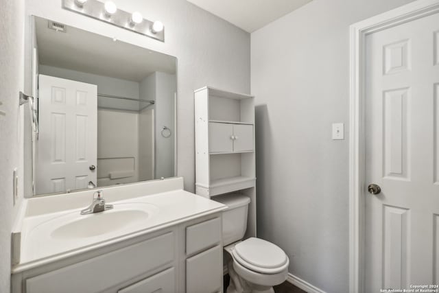 bathroom featuring vanity, toilet, and walk in shower