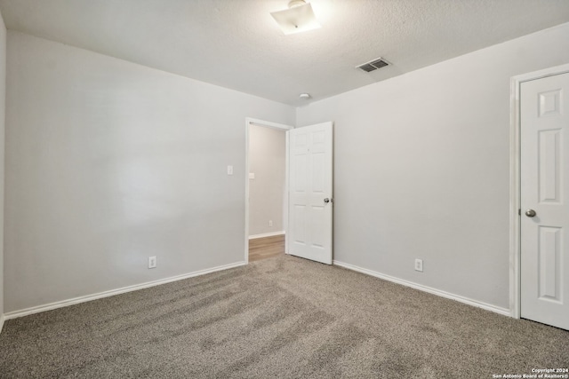 unfurnished room with carpet and a textured ceiling