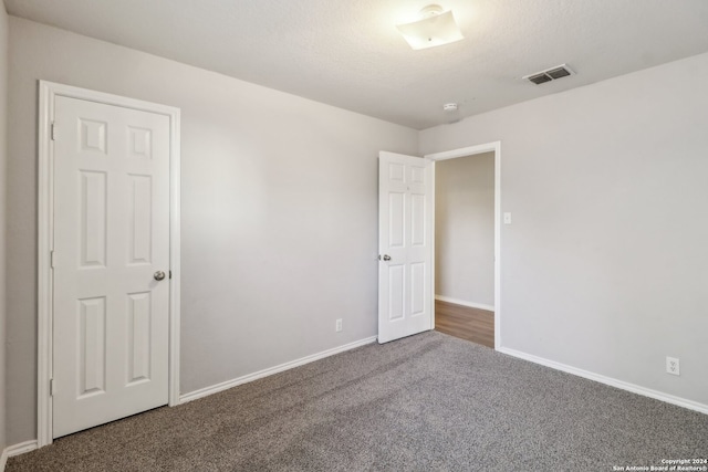 unfurnished room featuring dark carpet and a textured ceiling