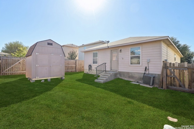 rear view of property featuring central AC, a yard, and a shed