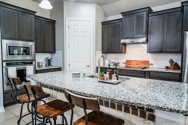 kitchen featuring light stone countertops, stainless steel appliances, and decorative backsplash