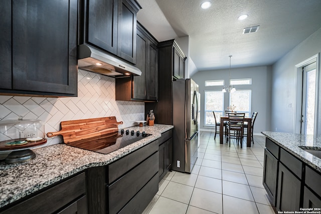 kitchen with black electric stovetop, light stone countertops, backsplash, a chandelier, and stainless steel refrigerator with ice dispenser