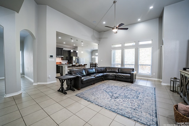 living room with light tile patterned floors, a high ceiling, and ceiling fan