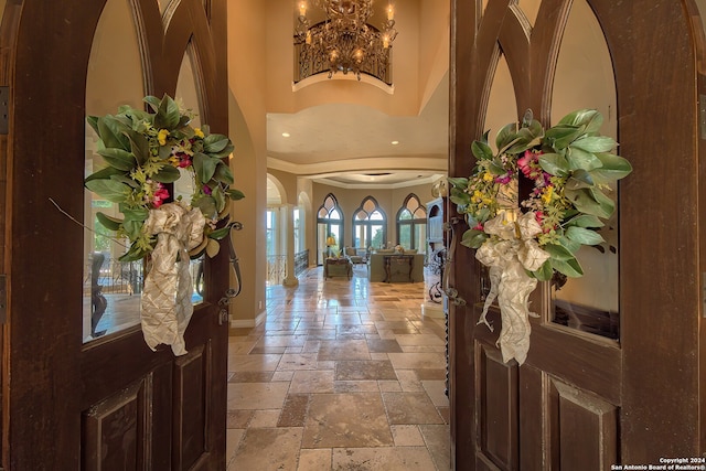 entrance foyer with a high ceiling, crown molding, and an inviting chandelier