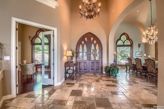 foyer with a notable chandelier, a healthy amount of sunlight, and a towering ceiling