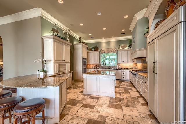 kitchen featuring tasteful backsplash, stone countertops, a center island, kitchen peninsula, and ornamental molding