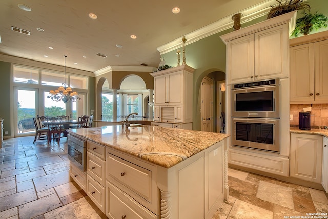 kitchen featuring decorative backsplash, a center island with sink, hanging light fixtures, ornamental molding, and stainless steel appliances