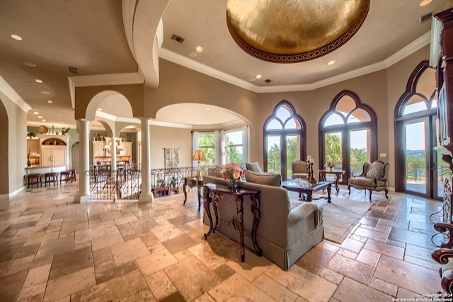 living room featuring crown molding, a high ceiling, a raised ceiling, and decorative columns