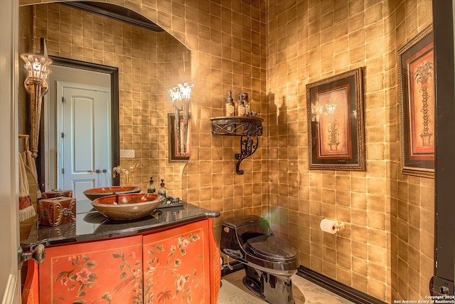 bathroom with tile walls, vanity, toilet, and tile patterned floors