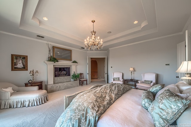 carpeted living room with a notable chandelier, a premium fireplace, a tray ceiling, and ornamental molding