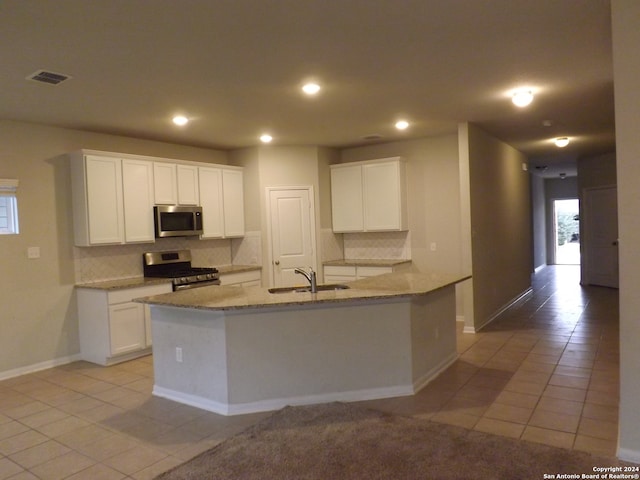 kitchen with sink, white cabinetry, light tile patterned floors, appliances with stainless steel finishes, and tasteful backsplash