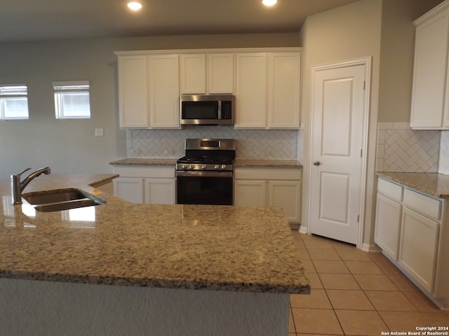 kitchen with decorative backsplash, white cabinetry, light tile patterned flooring, sink, and stainless steel appliances