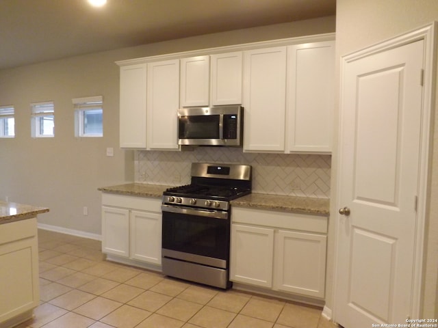 kitchen featuring white cabinetry, tasteful backsplash, stainless steel appliances, and light stone counters