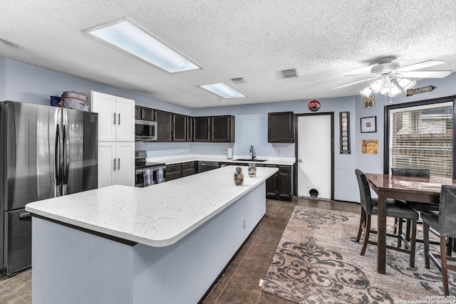 kitchen with a center island, a textured ceiling, stainless steel appliances, and sink