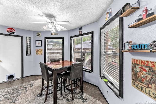 dining room with dark tile patterned flooring, ceiling fan, and a textured ceiling