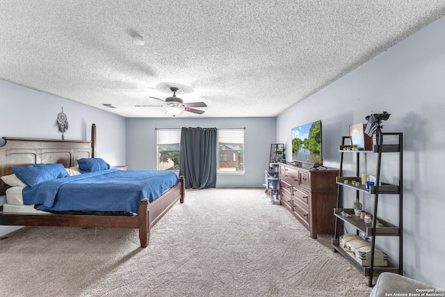 bedroom with a textured ceiling, light colored carpet, and ceiling fan