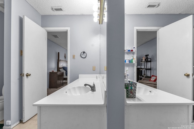 bathroom featuring vanity, toilet, tile patterned floors, and a textured ceiling