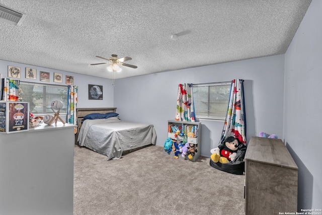 carpeted bedroom with ceiling fan and a textured ceiling