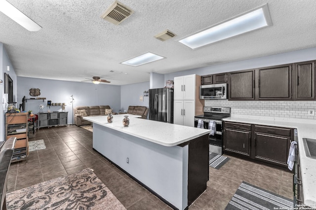 kitchen with a breakfast bar area, appliances with stainless steel finishes, a textured ceiling, and backsplash