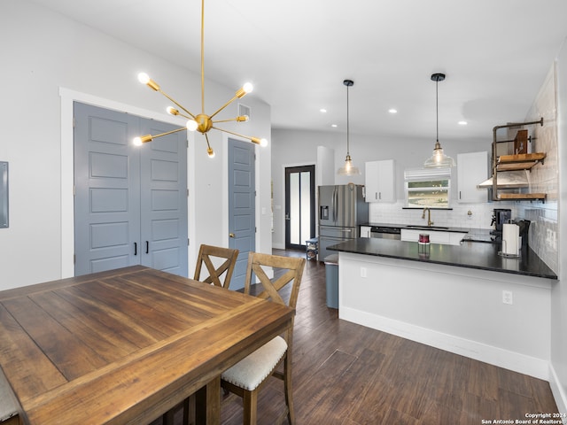 dining room featuring dark hardwood / wood-style floors, a chandelier, sink, and vaulted ceiling